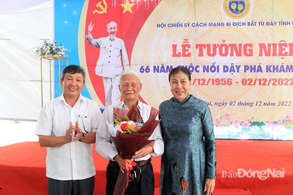 Phó bí thư thường trực Tỉnh ủy Hồ Thanh Sơn (bìa trái) và Chủ tịch Hội Chiến sĩ cách mạng bị địch bắt tù đày tỉnh Trần Thị Hòa (bìa phải) tặng hoa nhân chứng lịch sử. Ảnh: Nga Sơn