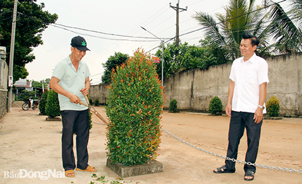 Ông Lê Thế Lực (bên phải) trò chuyện cùng người dân đang chăm sóc  cây xanh tại một tuyến đường trong khu dân cư. Ảnh: S.Thao